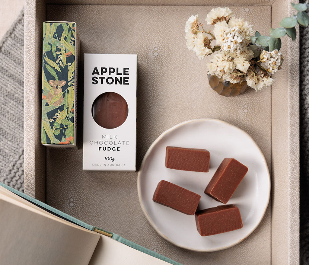 Apple Stone milk chocolate fudge on a plate with packaging and decorative elements.