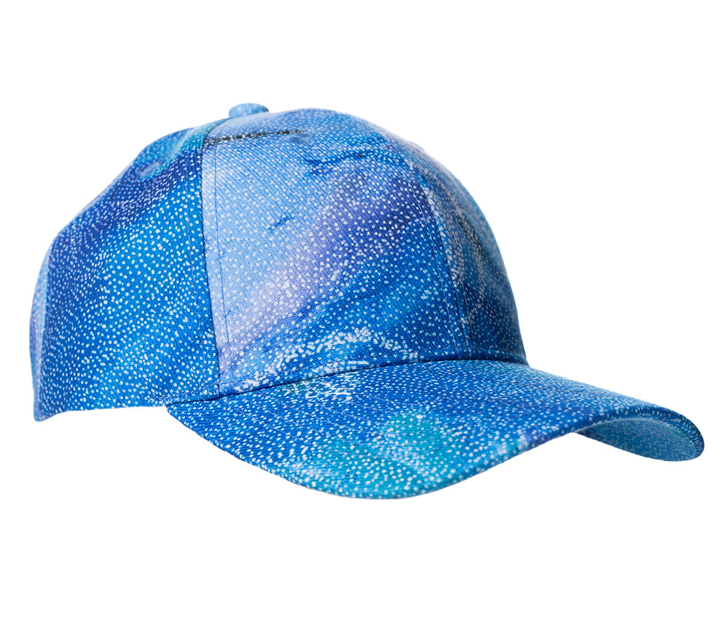 A baseball cap featuring Aboriginal artwork against a white background by Athena Granites courtesy Warlukurlangu Artists. 