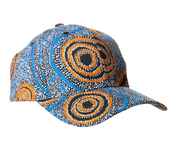 A baseball cap featuring Aboriginal artwork against a white background by Nigel Marshall courtesy Warlukurlangu Artists. 
