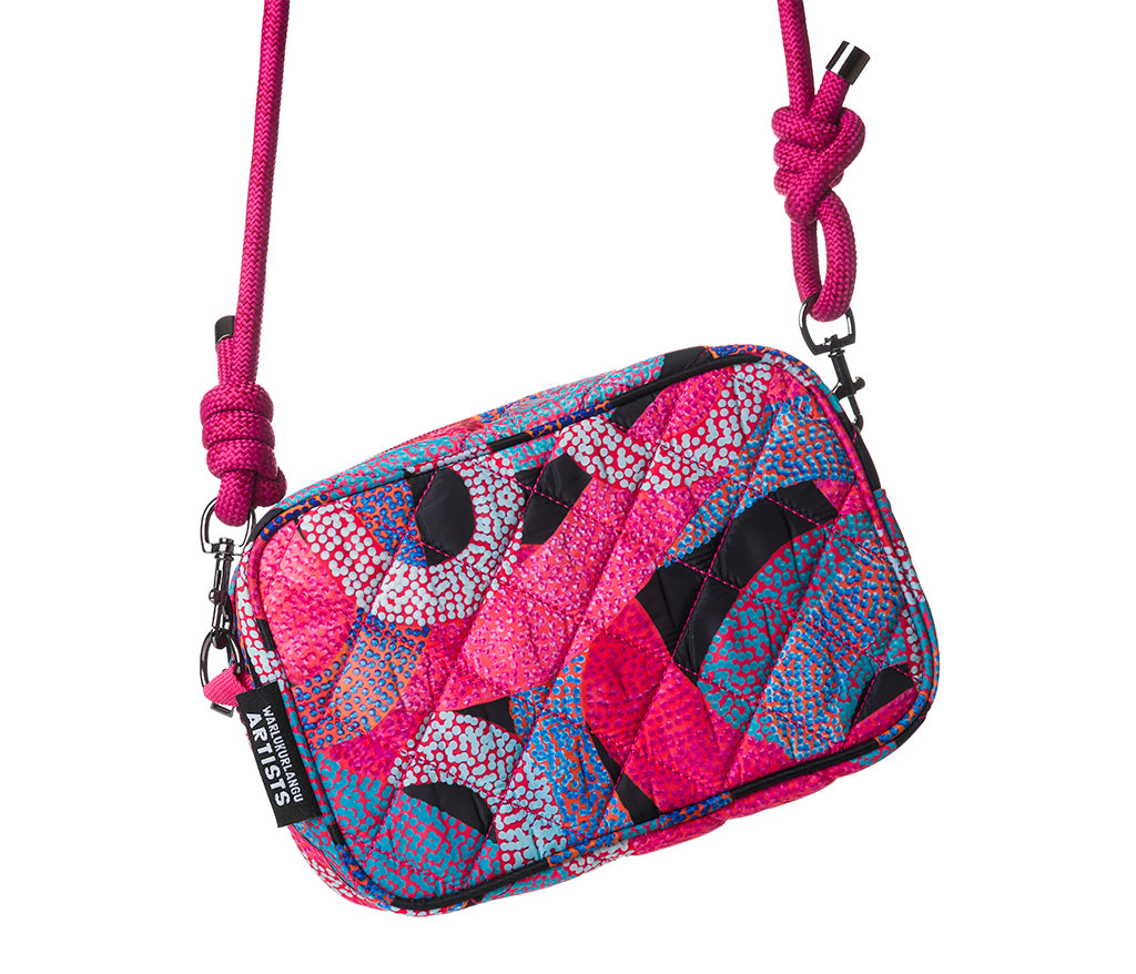 A quilted crossbody bag with Aboriginal Art by Vanetta Hudson, featuring a matching pink knotted shoulder strap.