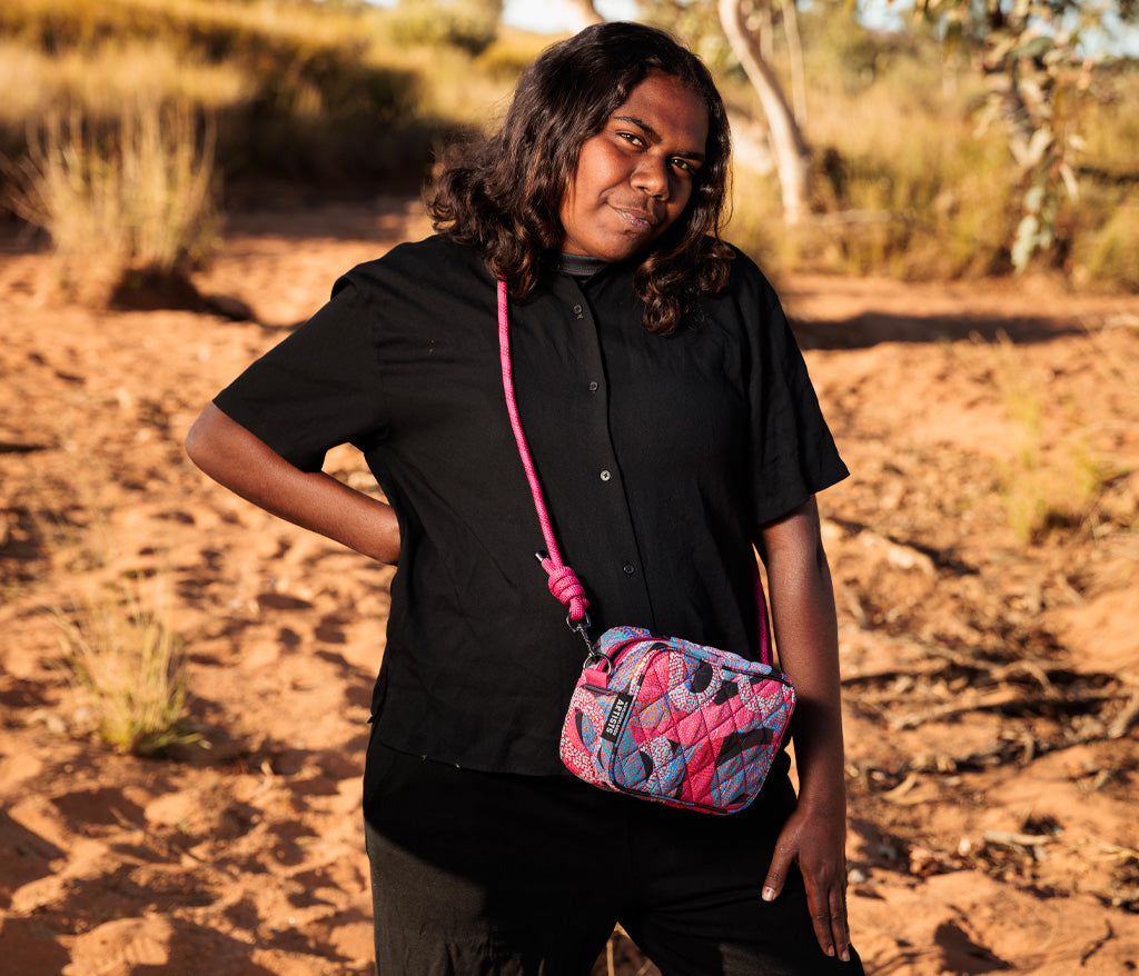 Vanetta Hudson standing outside wearing a Rope Cross Body Bag featuring her artwork.