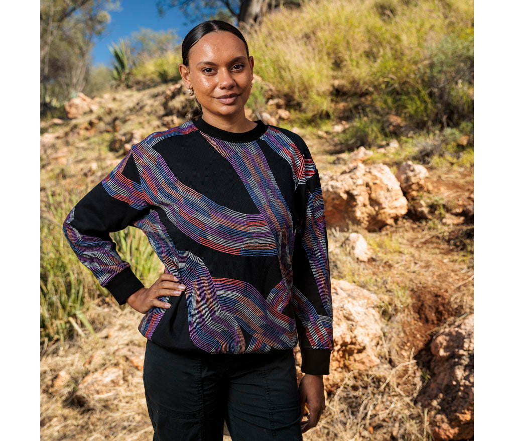 Model photographed outside wearing Flora Brown Aboriginal Art Sweatshirt