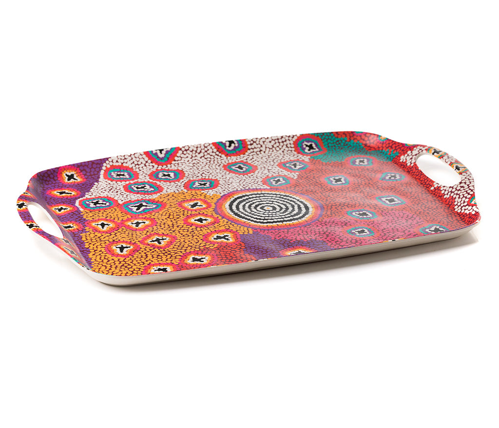 A rectangular bamboo/melamine serving tray with integrated side handles, featuring Aboriginal artwork byRuth Stewart from Warlukurlangu Artists. Image on a white background.