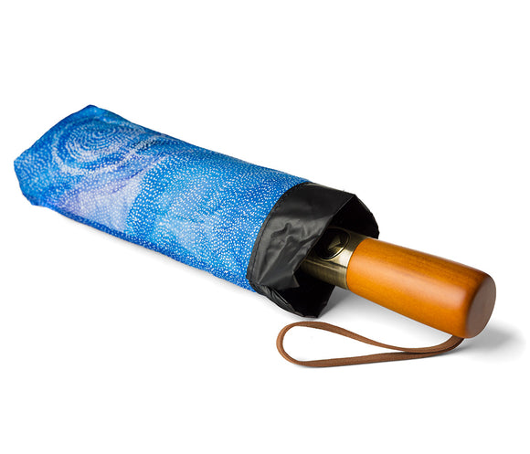 Fold Up Umbrella with wooden style handle and a black canopy photographed on a white background. Inside panels feature Aboriginal artwork by Athena Granites courtesy Warlukurlangu Artists