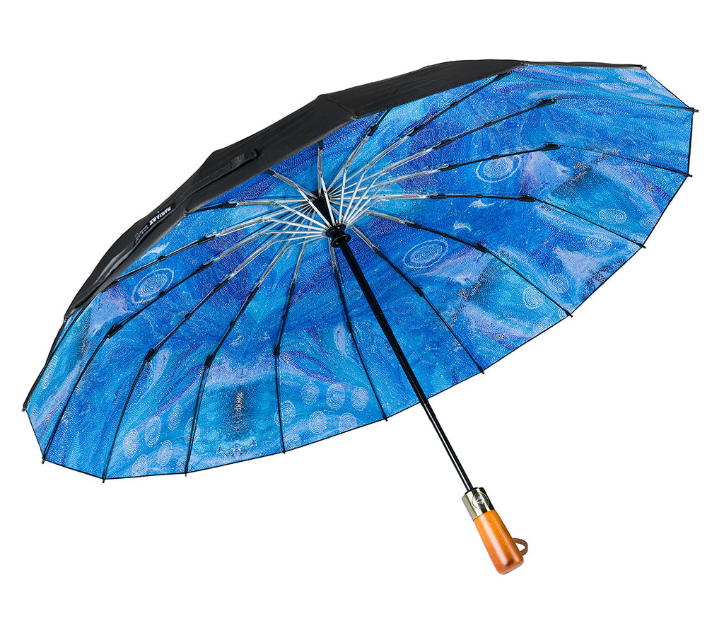 Fold Up Umbrella with wooden style handle and a black canopy photographed on a white background. Inside panels feature Aboriginal artwork by Athena Granites courtesy Warlukurlangu Artists
