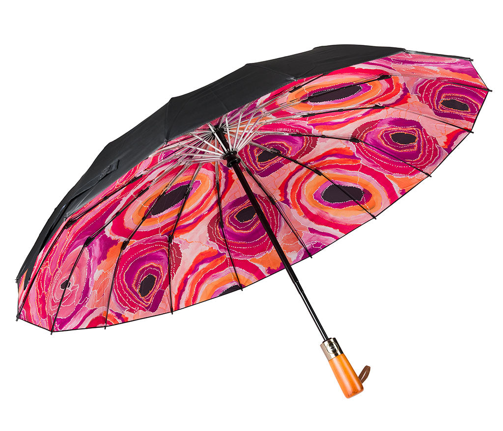 Fold Up Umbrella with wooden style handle and a black canopy photographed on a white background. Inside panels feature Aboriginal artwork by Steven Nelson courtesy Warlukurlangu Artists