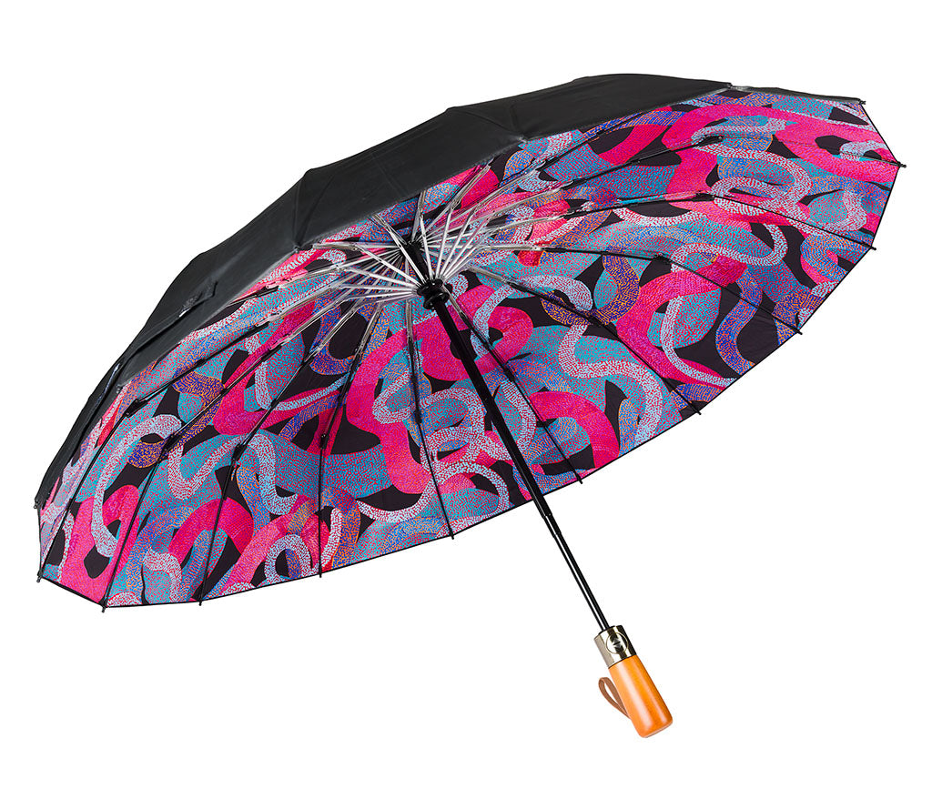 Fold Up Umbrella with wooden style handle and a black canopy photographed on a white background. Inside panels feature Aboriginal artwork by Vanetta Hudson courtesy Warlukurlangu Artists