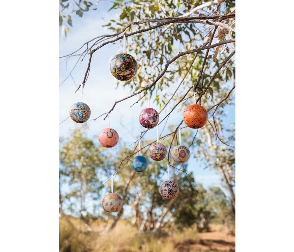 Aboriginal Art Christmas Baubles hanging from a tree branch outdoors