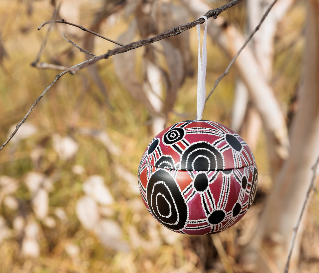 Bess Poulson Aboriginal Art Christmas Bauble hanging from a branch.