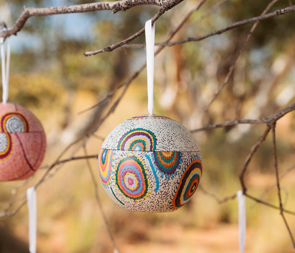 Jeanie Ross Aboriginal Art Christmas Bauble hanging on a branch.
