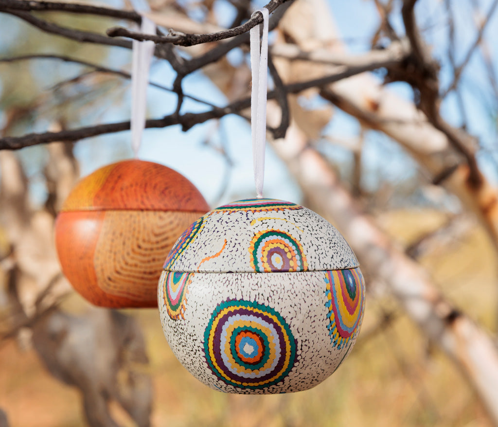 Jeanie Ross Aboriginal Art Christmas Bauble hanging from a branch.